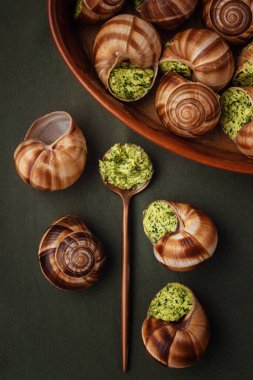 yeşil bir masada sosa batırılmış salyangoz.