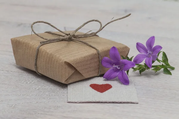 Pequeño regalo con flor y corazón — Foto de Stock