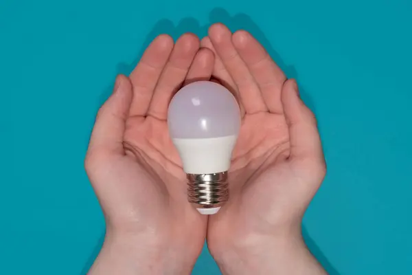 Mavi arkaplanda elinde ampul.
