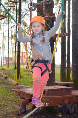 Kız yüksek halat kursuna tırmanıyor maceranın tadını çıkarıyor