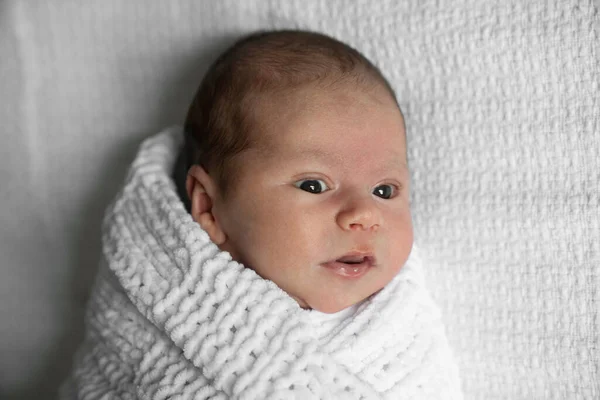 Memnun oldum. Yatakta yatarken beyaz battaniyeye sarılı sevimli yeni doğmuş bebek. Mutlu çocukluk kavramı. Stok fotoğrafı