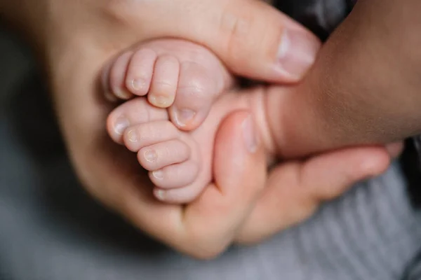 Anne bakımı. Kafkasyalı annenin, yeni doğmuş oğlunun bacaklarını tutarken onunla kanepede vakit geçirmesini yakından izleyin. Annelik kavramı. Stok fotoğrafı
