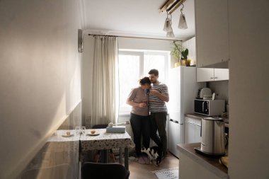 Mutfakta durup birbirleriyle kaynaşırken siyah ve beyaz kedileriyle kahve içen mutlu aile manzarası. Sabahları sevimli bir çift. Stok fotoğrafı