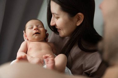 Birlikte çok güzel vakit geçirdik. Sevimli beyaz anne, tatlı bebeğinin kafasını okşuyor ve onu ellerinin arasında tutuyor ve birlikte vakit geçiriyorlar. Kocası bebeğine bakıyor. Stok fotoğrafı