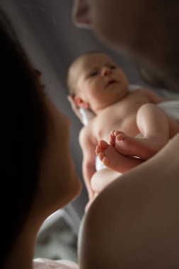 Birbirlerine şefkatli bir şeyler anlatırken, ebeveynlerin çocuklarını ellerinden tuttukları görüntüler. Bebeğin bacaklarına odaklan. Stok fotoğrafı