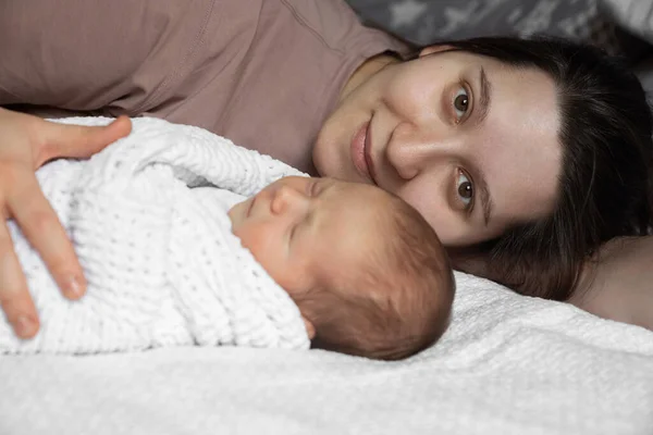 Anne kızın yeni doğmuş bebeğiyle yatıp kameraya şefkatle baktığı portre görüntüsü. Stok fotoğrafı