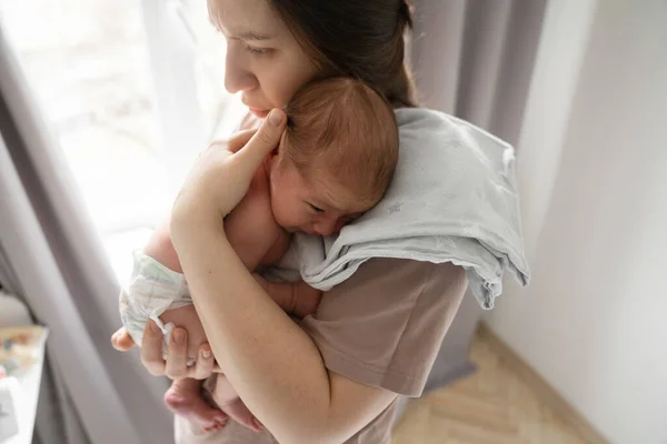 Aşkım. Beyaz bir kadının yatak odasında onunla vakit geçirirken ağlayan küçük bebeğini sakinleştirdiği yüksek açı görüntüsü. Stok fotoğrafı
