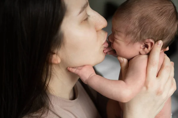 Keep calm. Cropped view of the adorable caucasian woman calming her little crying baby while spending time with him at the bedroom. Stock photo