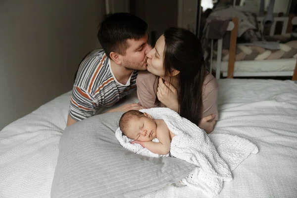 Seni seviyorum, canım. Neşeli karı koca portresi. Yeni doğmuş çocuklarıyla yatakta yatarken birbirlerini öperler. Mutluluk kavramı. Stok fotoğrafı