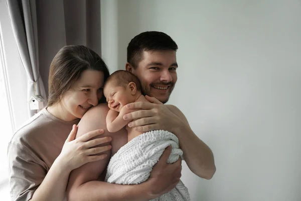 Mutlu ebeveynlik izinleri. Ebeveynler sevimli bebekleriyle eğlenirken, onu ellerinden tutup şefkatle gülümsüyorlar. Stok fotoğrafı