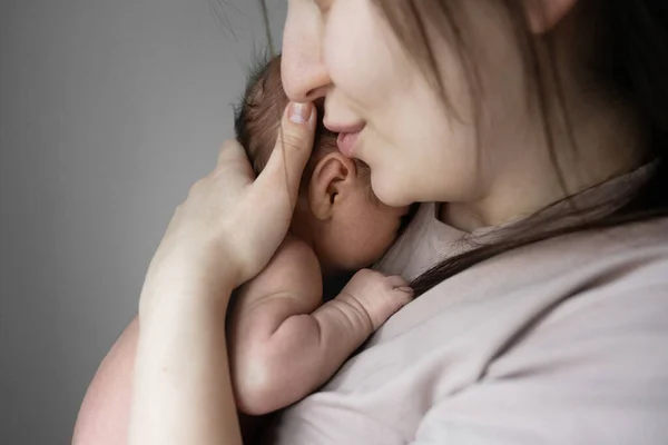 Dünyanın en büyük aşkı. Genç esmer anne, sevimli bebeğini öperken, onunla rahat bir odada kalıyor. Stok fotoğrafı. Annelik ve mutlu çocukluk kavramı