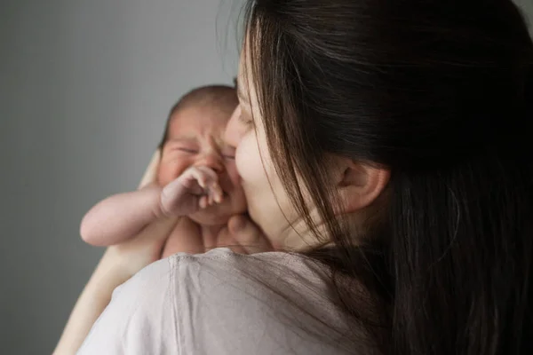 Ağlamayın. Sevimli, dost canlısı annenin, yeni doğmuş bebeğini rahat oturma odasında otururken sakinleştirdiği arka plan. Stok fotoğrafı