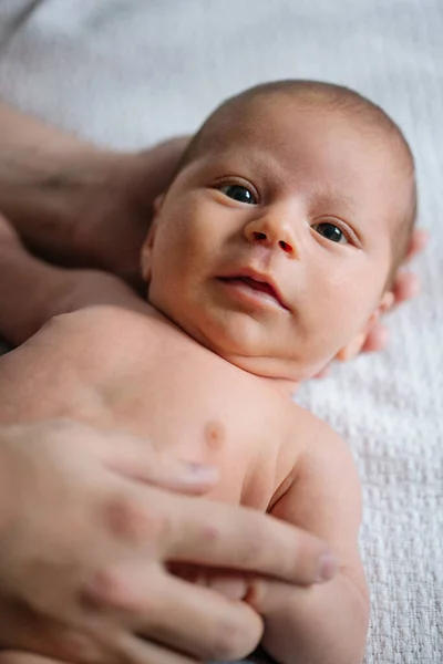 Yatakta çıplak yatan ve hayatının ilk ayının tadını çıkaran yeni doğmuş bebeğin en güzel görüntüsü. Küçük çocuk kameraya bakıyor. Stok fotoğrafı 