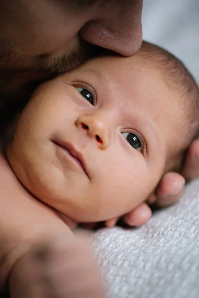 Benim güzel oğlum. Sakallı, sakalsız beyaz bir adam yeni doğmuş bebeğini yatakta tutuyor ve onunla eğleniyor. Tatlı çocuk başka tarafa bakıyor.