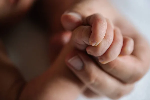 Çok az. Yeni doğan oğlunun elini tutan kadının el ele tutuşunu özenle ve şefkatle seyrediyor. Stok fotoğrafı. Mutlu annelik kavramı