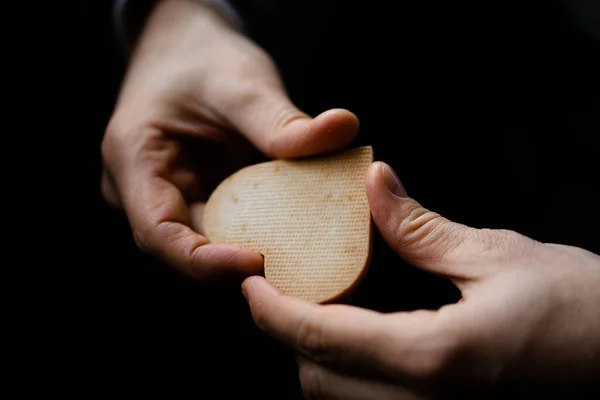 Bisküviyi kalp şeklinde tutan ve kameraya gösteren mutlu adamın yakın görüntüsü. Kurabiyeli bir adamın ellerine odaklan, adamın vücudu arka planda bulanıklaşır.