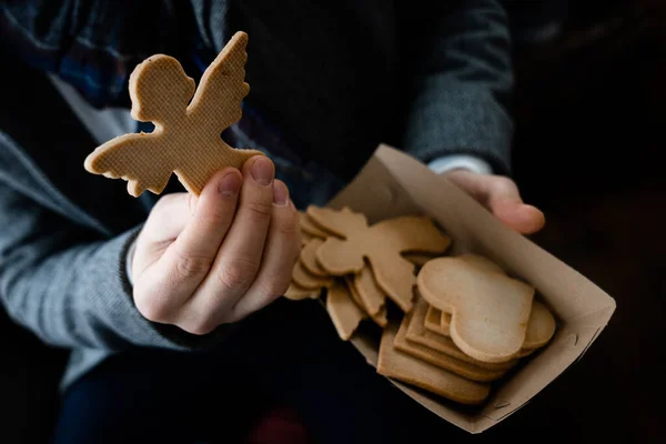 Farklı şekillerdeki bisküvileri tutan adamın yakın görüntüsü ve el işi karton kutu. Tatiller ve tatlı kurabiye konsepti. Stok fotoğrafı