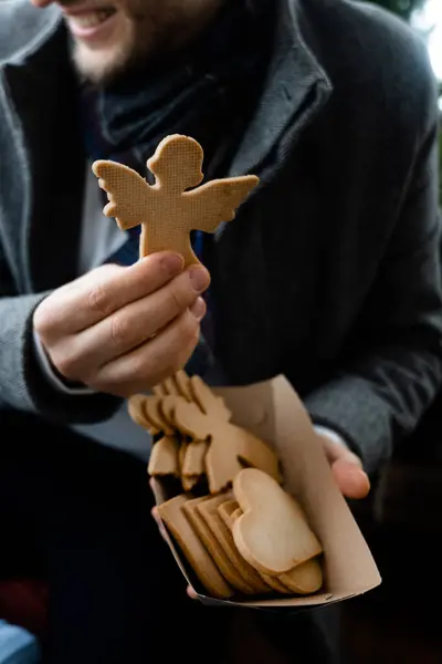 Farklı şekillerde bisküvi tutan, kağıt kutu hazırlayan ve gülümseyen adamın yakın görüntüsü. Tatiller ve tatlı kurabiye konsepti. Stok fotoğrafı