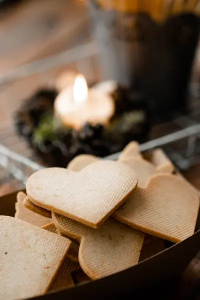 Çok lezzetli. Mumun yanındaki ahşap pencere pervazındaki el işi kağıt kutuda duran kalp şekilli bisküvileri yakından izleyin. Tatlı kurabiye konsepti. Stok fotoğrafı