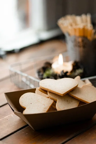 Farklı şekillerdeki lezzetli bisküvilerin dikey görüntüsü el işi kağıt kutunun üzerinde duruyordu. Pencerenin kenarında, mumun yanında duruyordu. Arka planda kış manzarası. Tatlı kurabiye konsepti. Stok fotoğrafı
