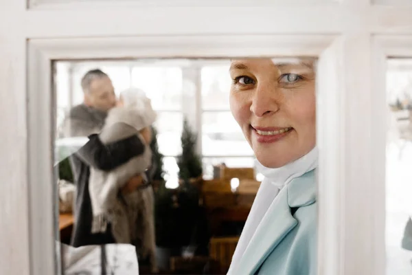Kocasının arka planda oğluyla yakınlaşırken zevkle pencereye bakan kısa saçlı kadının portre görüntüsü. Stok fotoğrafı