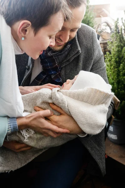 Şefkatli bakım. Genç beyaz anne babalar balkonda tatlı bebeklerini kucaklarken ona şefkatle bakıyorlar. Ebeveynlik ve mutlu çocukluk kavramı