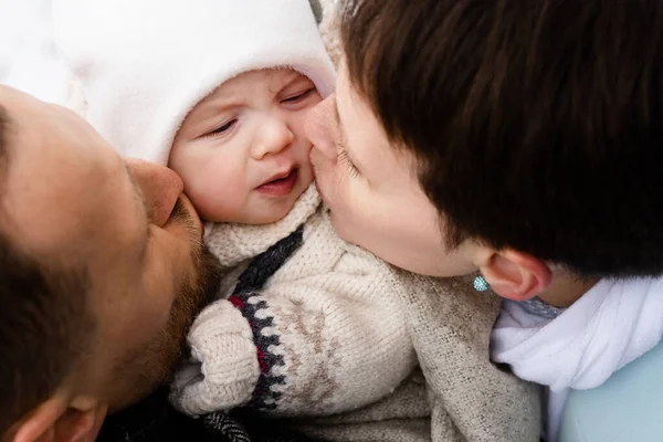 Koyu saçlı beyaz bir çiftin sokakta yeni doğmuş güzel bebeklerini öptüğü ve onunla eğlendiği görüntüler. Ailesinin arasında sevimli bir çocuk.