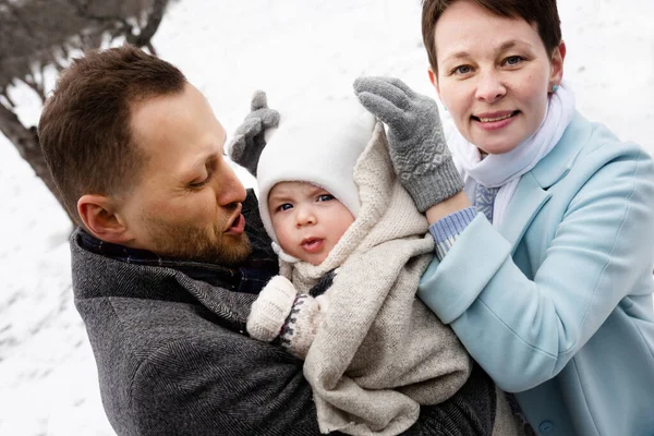 Birlikte iyi vakit geçirin. Sevimli beyaz kadın tatlı bebeğinin şapkasını düzeltirken kocası da onu ellerinden tutup birlikte vakit geçiriyordu. Kocası bebeğine bakıyor. Stok fotoğrafı