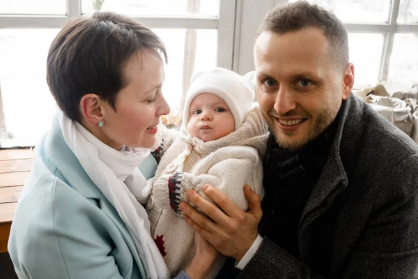 Yeni doğan çocuğumuz. Güzel, beyaz, siyah saçlı bir çift yeni doğmuş güzel bebeklerini ellerinde tutuyorlar ve onunla eğleniyorlar. Annesinin ellerinde oturan ve kameraya bakan sevimli çocuk.