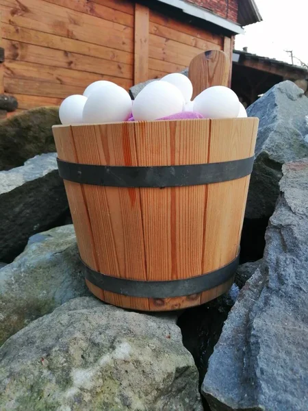 Easter mountain theme. A wooden bucket full of white eggs placed on large stones evokes the feeling of Easter in a mountain evironment. An environment full of peace, harmony and solitude.