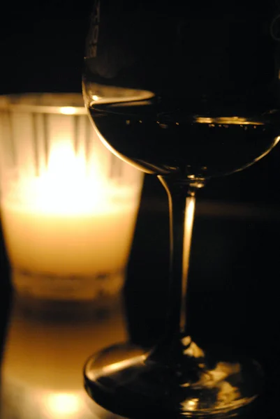 Titreyen bir mumun önünde duran kırmızı bir şarap.