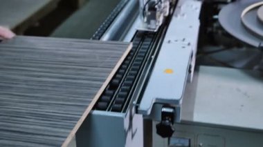 İşçinin bir kontrplak kenar bantlama makinesi koyar.