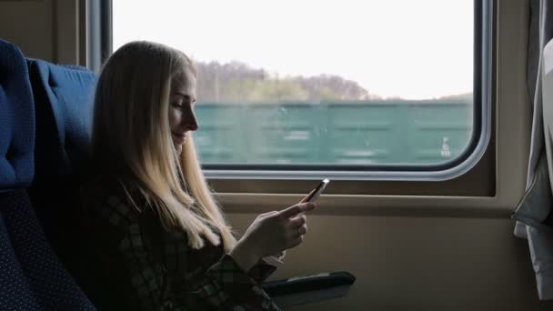 Jovem mulher usando smartphone enquanto viaja de trem — Vídeo de Stock