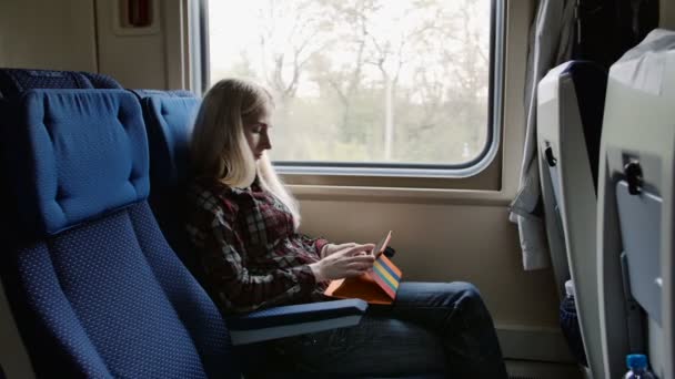 Mladá žena pomocí tabletu v barevné věci při cestování vlakem — Stock video