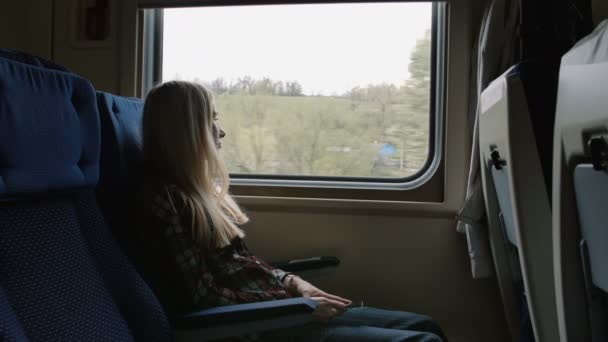 Jeune femme caucasienne regarder à travers la fenêtre tout en voyageant en train — Video