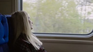 Trenle seyahat ederken genç beyaz kadın bakmak sokmak belgili tanımlık pencere