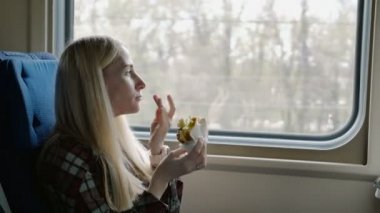 Güzel kadın tren yolculuğu sırasında sandviç yeme