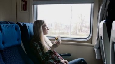 Güzel kadın tren yolculuğu sırasında sandviç yeme