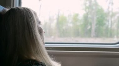Trenle seyahat ederken genç beyaz kadın bakmak sokmak belgili tanımlık pencere