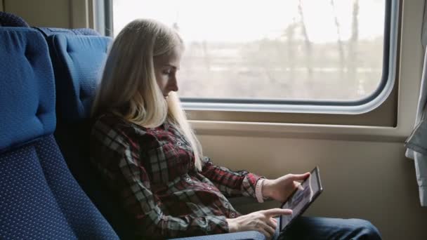 Молодая женщина использует планшет во время путешествия на поезде — стоковое видео