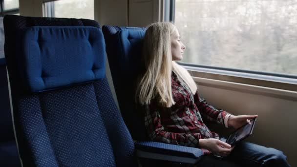 Mujer joven usando tableta mientras viaja en tren — Vídeo de stock