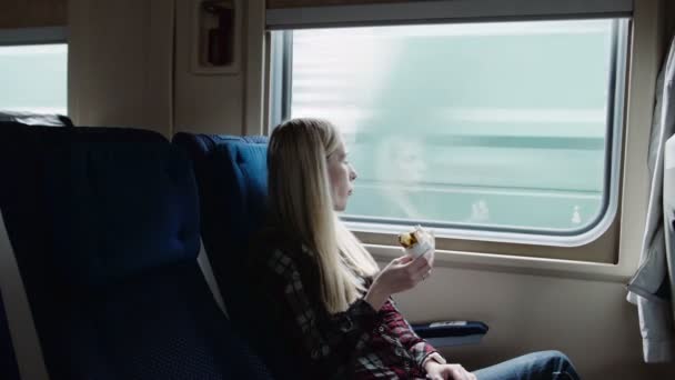 Красива жінка їсть бутерброд під час поїздки на поїзді — стокове відео