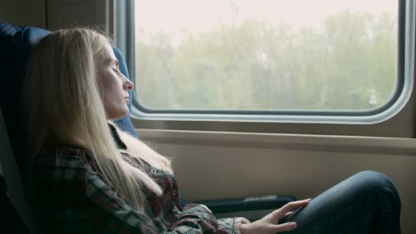 Mujer joven caucásica mira a través de la ventana mientras viaja en tren — Vídeo de stock