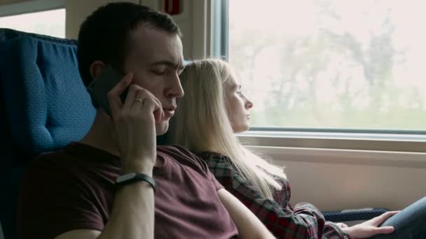 Boos jongeman praten met iemand op een telefoon in een rijdende trein — Stockvideo