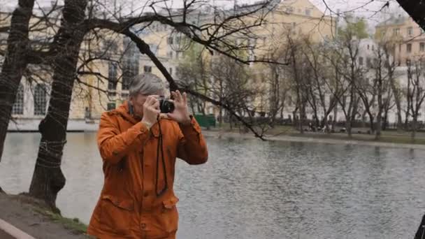 Взрослый фотограф рассказывает, как позировать и фотографировать со старой винтажной пленочной камерой — стоковое видео