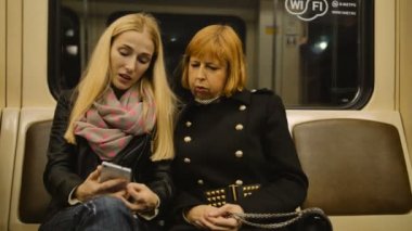 Genç ve yaşlı söz ve metroda cep telefonu kullanan kadınlar