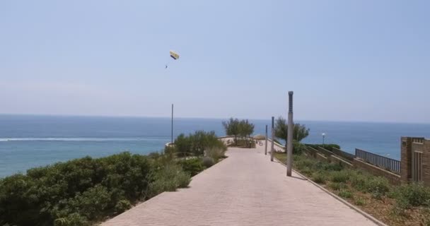 Turista. létající pod padákem. je vlečen zprava doleva přes rám v moři — Stock video