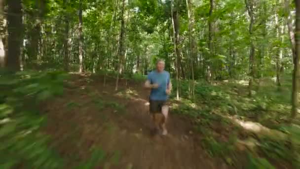 Homem adulto correndo correndo ao ar livre em uma natureza florestal em uma trilha florestal e apreciando e parecendo feliz — Vídeo de Stock