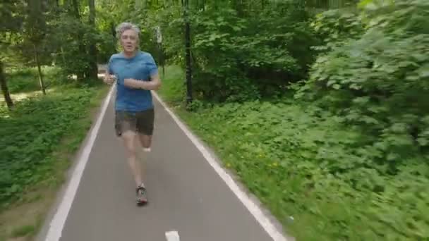 Volwassen man loopt joggen buiten in de natuur van een bos op een bospad en genieten van het kijken gelukkig — Stockvideo
