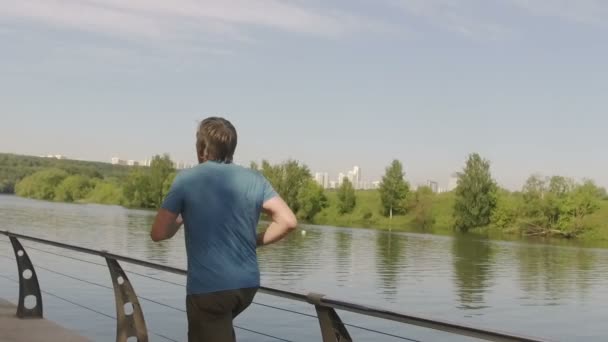 Anciano entrenando en terraplén contra el río por la mañana en cámara lenta — Vídeo de stock